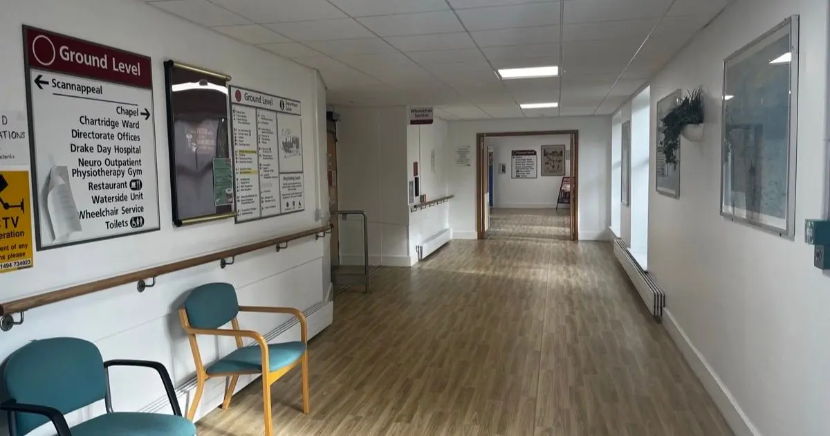 An empty hospital corridor with chairs along one wall and direction signs at Amersham Hospital, Buckinghamshire